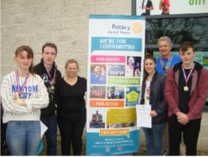 EYAI young adults and supporters with their medals beside a Rotary community banner