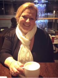 Jo Brown smiling over a cup of coffee at a café table